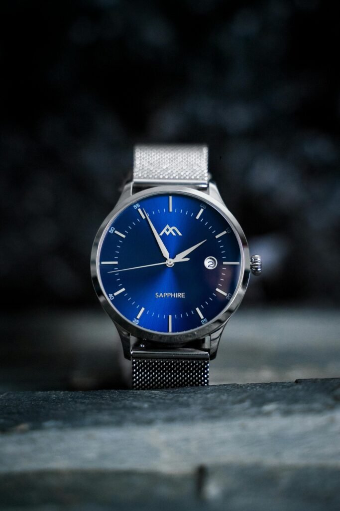 Close-up shot of an elegant wristwatch with a blue sapphire dial and metal mesh strap.